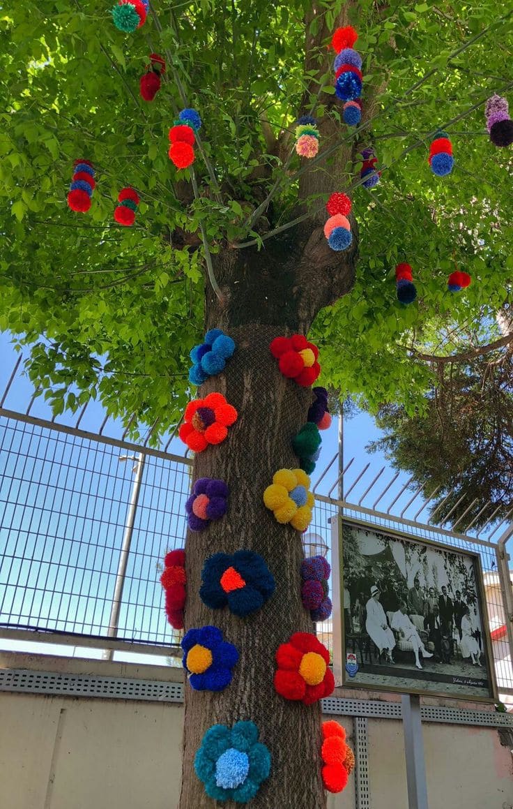 20 Whimsical Tree Trunk Projects That Transform Your Outdoor Space Yarn-Bombed Tree with Pom-Pom Blooms